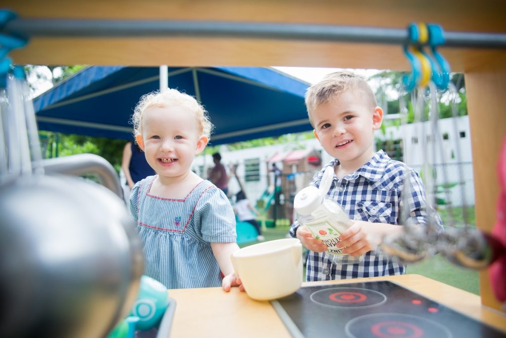 two children playing cooking outdoors