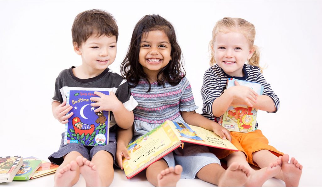 Three smiling children reading