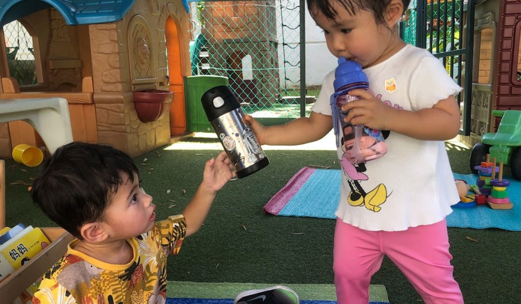 two preschoolers drinking water
