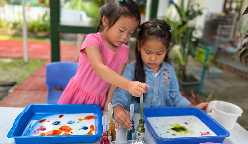two preschoolers engaged in an artwork
