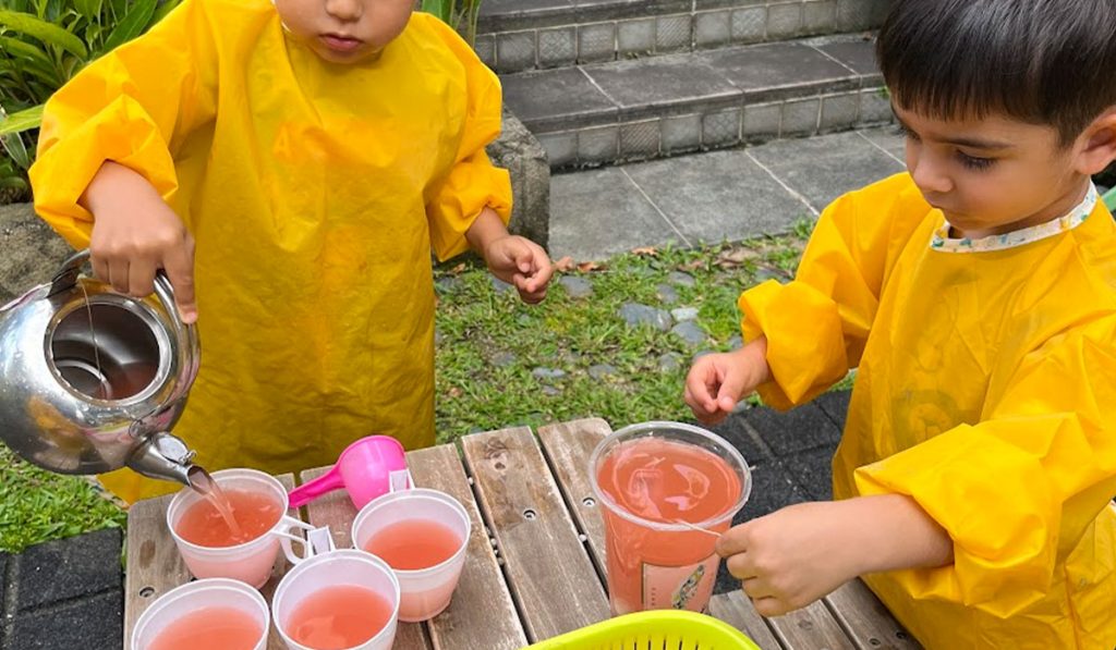 preschoolers pouring water from kettle to cup
